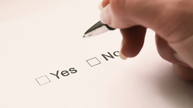 Man's hand with a pen over the document, select Yes or No. Close-up.