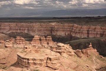 Hoodoos of Charyn Canyon National Park in sun with distant Tien Shen mountains Kazakhstan