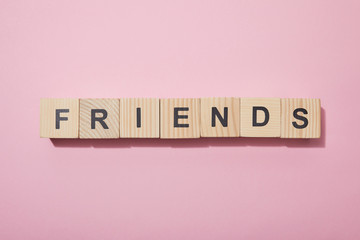 top view of wooden cubes with letters on pink surface