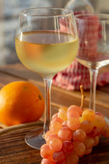 Aperitif cold white wine served in glasses with pink grapes on outdoor tessace witn sea view