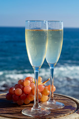 Champagne, prosecco or cava served with pink grape in two glasses on outside terrace with sea view