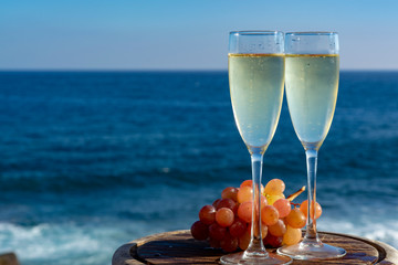 Champagne, prosecco or cava served with pink grape in two glasses on outside terrace with sea view