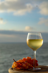 Aperitif cold white wine served in glasses with pink grapes on outdoor tessace witn sea view