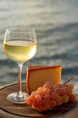 Spanish goat milk cheese with paprika coating and ripe pink table grapes served with white wine on outdoor terrace