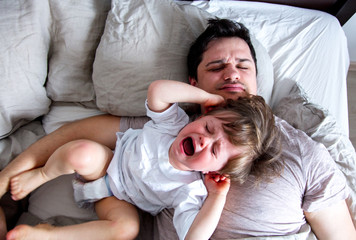 Little baby cry on a father when he do not want to wake up