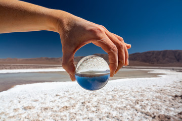Fototapeta na wymiar Hand holding glass ball at salt lakes in Atacama