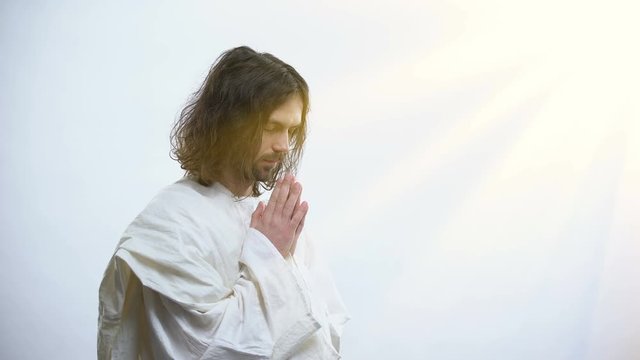 Religious man praying to God, light falling as sign of forgiveness, God mercy