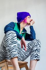 Woman with pink hair and zebra print jeans sitting on a stool