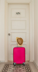 Pink suitcase on front of the hotel room door