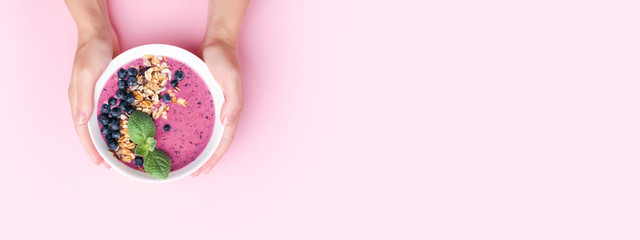 Hands holding smoothie bowl.