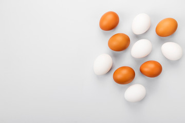 Group of raw eggs white and brown. Concept of diversity, isolation, racism, inequality. On gray background. Top view, copy space