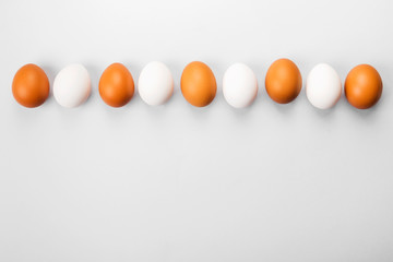 Group of raw eggs white and brown. Concept of diversity, isolation, racism, inequality. On gray background. Top view, copy space
