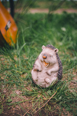 Close-up garden figurine decoration cheerful hedgehog on a blurred green background of grass and guitar