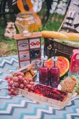 Fototapeta na wymiar Close-up design summer picnic in nature. On the plaid is a basket of food. On blurred background of a bicycle and decorative ornaments