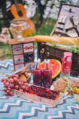 Fototapeta na wymiar Close-up design summer picnic in nature. On the plaid is a basket of food. On blurred background of a bicycle and decorative ornaments
