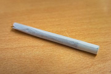 Handmade cigarette with paper filter lying on wood
