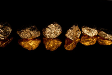 gold shiny stones in row with reflection isolated on black with copy space