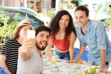 Group of friends taking selfie in cafe