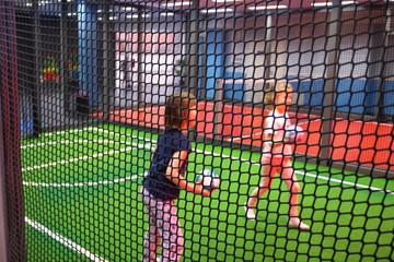 Blurred children are playing behind the net at indoor playground in activity park.