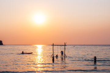Fototapeta premium Tourists play in the water sea during the sunset at area ao bang bao Koh kood island Trat, Thailand.