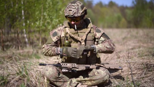 A warrior or military soldier dressed in camouflage With a cigarette in his mouth, he took off his glove and opened the package with matches.