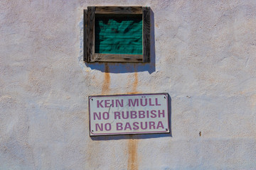 No rubbish sign in German, English and Spanish on the dirty wall - Image