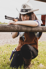 Fototapeta premium Portrait of a beautiful Chinese female cowgirl shooting with a weapon