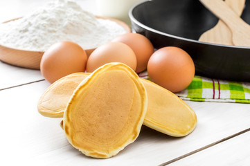 Pancakes with ingredients for cooking pancakes on the table.