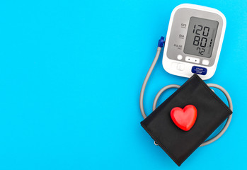 Blood pressure tonometer with red heart on blue background. Medical concept. Top view. Space for...