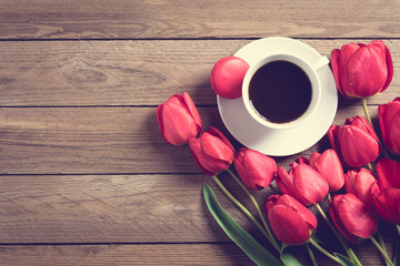 Row of red tulips and cup of black coffee americano on wooden background with space for text, message. Mother's Day, Hello spring, good morning concept. Card. Flat lay. Top view. Rustic style. 