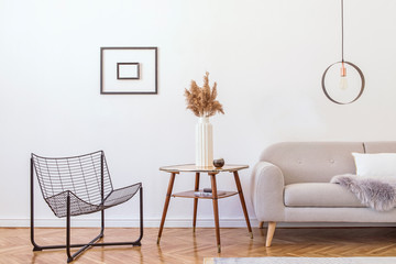 Stylish minimalistic living room with design grey sofa, black armchair, geometric lamp, retro table...