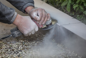 worker grinds granite stone with an diamond electric saw blade 