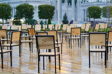 Wooden chairs stand in the rain outside