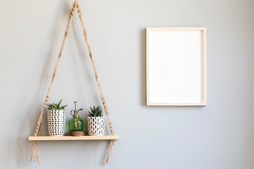 Stylish and minimalistic scandinavian interior with mock up poster frame and hanging wooden shelf...