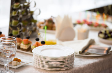 A stack of white plates on the table of the buffet table
