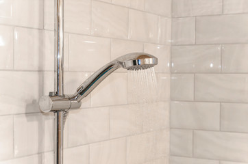 tap in bathroom, water flows from the shower, running water. the white background of the tiles