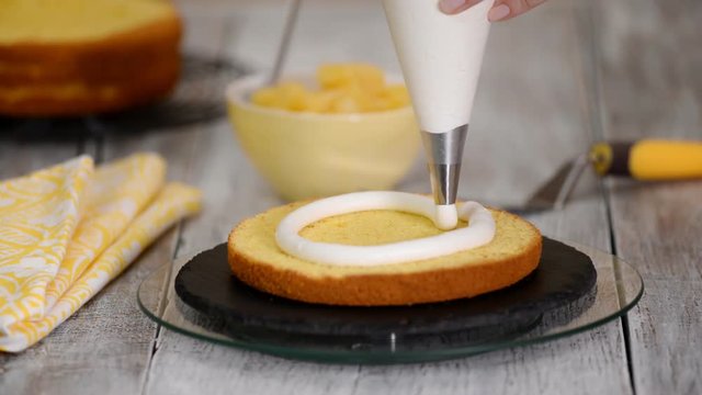 Pastry chef in the kitchen decorating a cake. Making cake with pineapple filling.