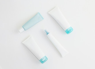 Composition of blue and white cosmetic tube mockups on white background. Flat lay.