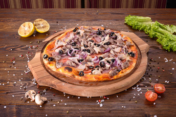 Meat pizza with beef chicken, pork, bacon, red onions and olives on a wooden Board.