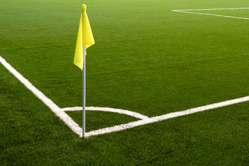 Yellow flag on the corner of a football field. White line marking sports field for football players. Place for a corner kick on a soccer ball.