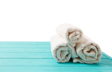 Obraz na płótnie Canvas Rolled white towels on blue wooden table isolated on white background. Copy space and top view. Bathroom objects for shower body treatment. Selective focus. Banner