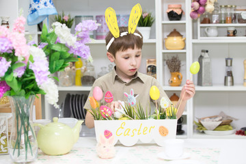 Boy with painted ears playing with easter eggs