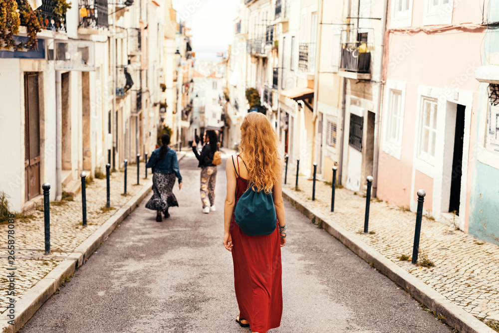 Wall mural Woman in red dress exploring narrow streets of european city streets