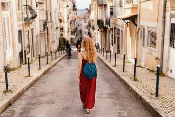 Woman in red dress exploring narrow streets of european city streets - obrazy, fototapety, plakaty