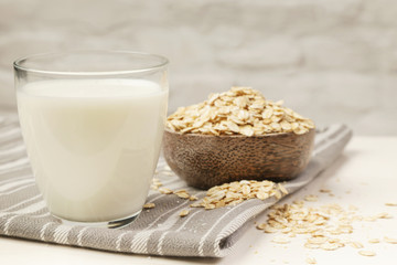 Oat milk and rolled oats. Organic vegan non-dairy plant-based milk in a glass.