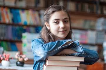 beautiful schoolgirl sitting in the library with books