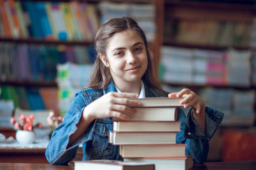 beautiful schoolgirl sitting in the library with books