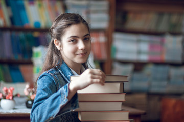 beautiful schoolgirl sitting in the library with books