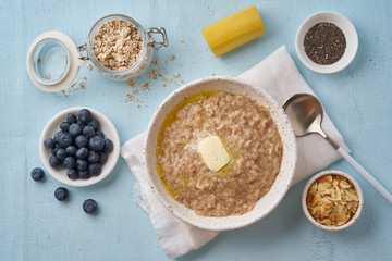 Oatmeal with butter and toppings. Blueberries, Chia seeds, almond flakes, banana. Top view