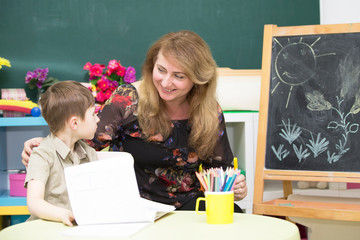 Teacher with a preschooler. Woman with a junior student in a bright children's room
